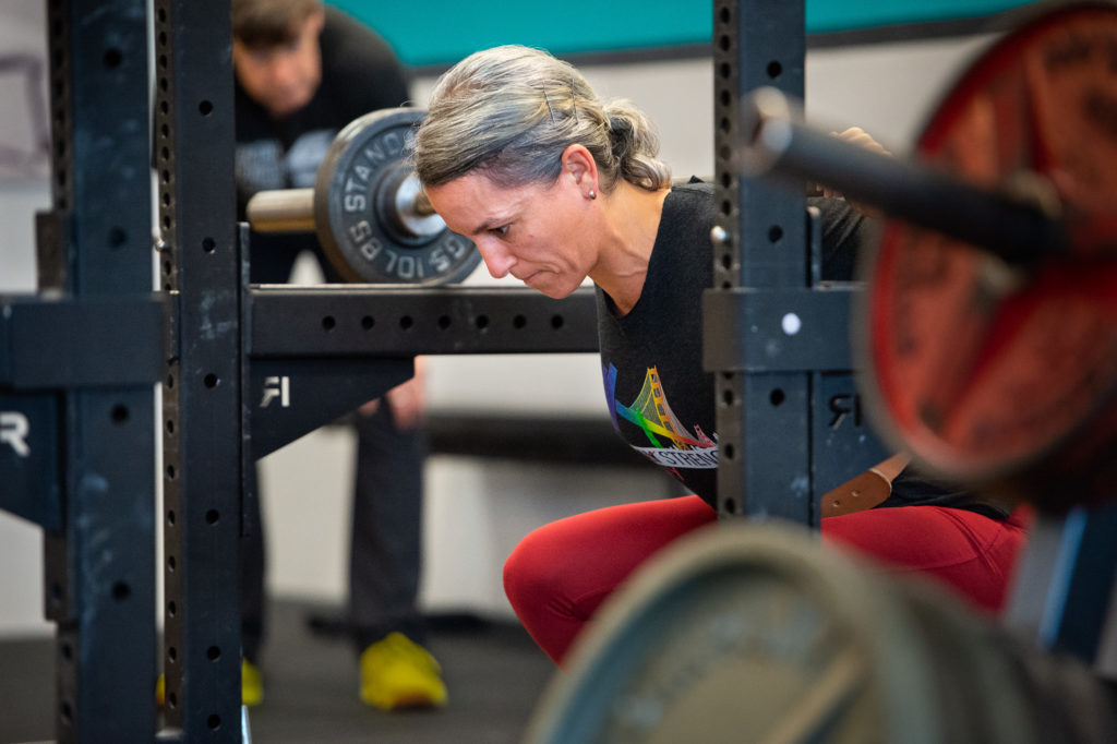 Lifter squatting with coach watching